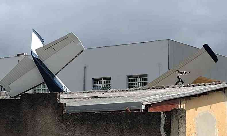 Foto mostra parte do avio que caiu e ficou entre os muros de duas casas