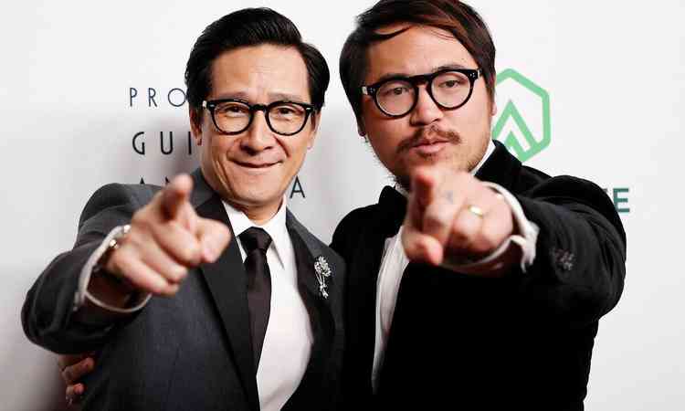 Ke Huy Quan e Daniel Kwan, ator e diretor de 'Tudo em todo lugar ao mesmo tempo' esto abraados e apontam para a cmera