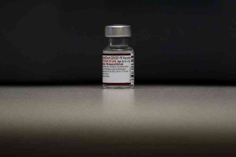 Um frasco da vacina contra a covid-19 em um fundo preto.