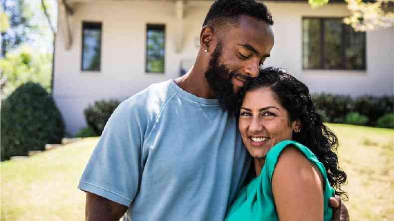 Um jovem casal multiracial se abraa e sorri