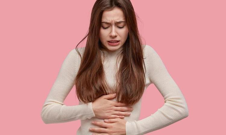 moça com as duas mão sobre a barriga com expressão de dor
