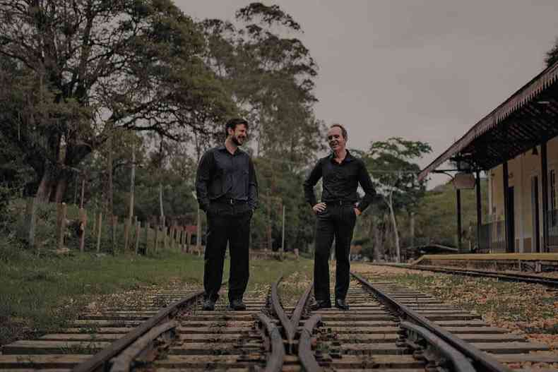 Pianistas Gustavo Carvalho e Cristian Budu caminham sobre a linha de trem, em Tiradentes