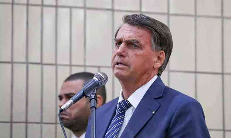 Presidente Jair Bolsonaro, em p, enquanto discursa com um microfone