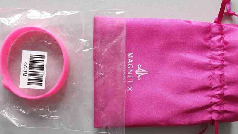Uma pulseira cor-de-rosa ao lado de uma embalagem da mesma cor