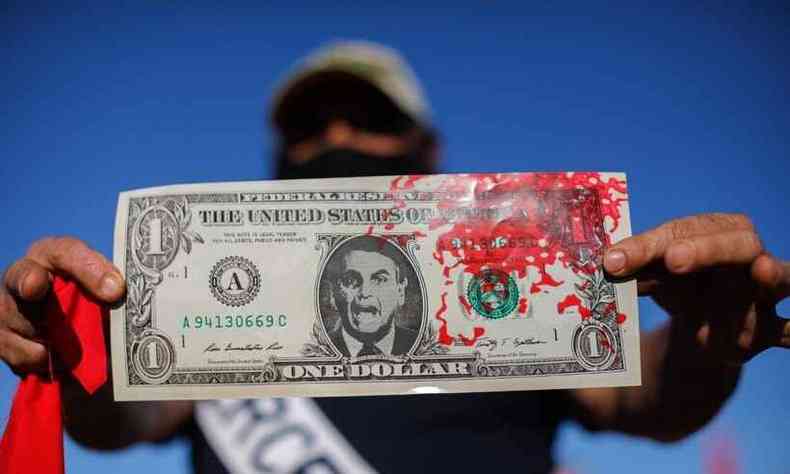 Manifestante a favor de impeachment de Bolsonaro exibe nota de US$ 1 com face do presidente e manchada de sangue(foto: Sergio LIMA / AFP)