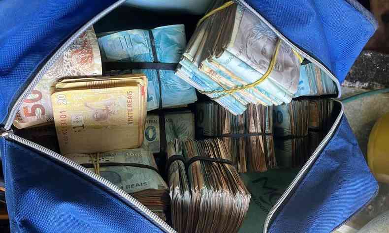 Bolsa azul contendo diversos blocos de dinheiro