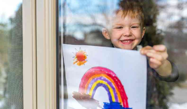 Menino mostrando imagem com desenho de arco ris