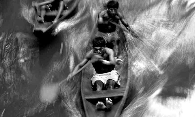 Fotografia em preto e branco de Elza Lima mostra homem navegando em canoa 