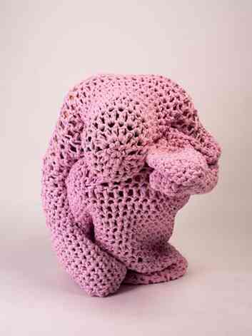 Escultura de croch cor-de-rosa remete a figura humana em momento de dor
