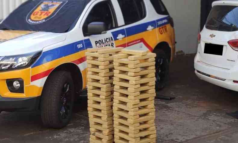 Tabletes de maconha empilhados  frente de uma viatura policial