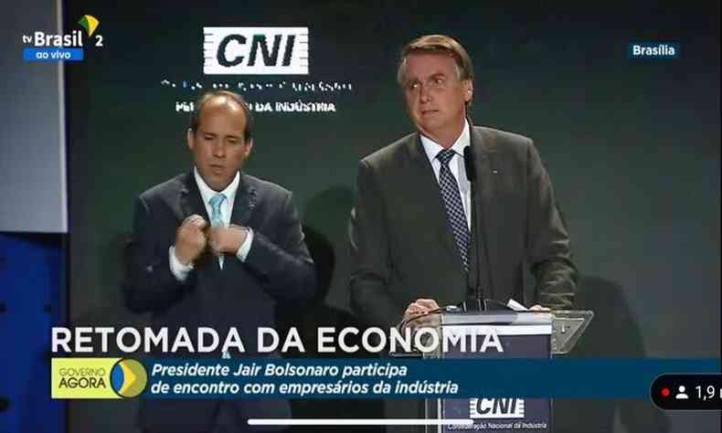 Presidente Jair Bolsonaro fala ao microfone durante encontro com empresrios; atrs aparece um painel com a logomarca da CNI (Confederao nacional da Indstria) 