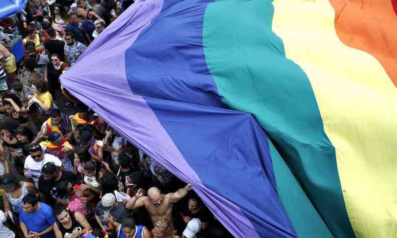 Bandeira com as cores do arco-íris cobre um grande grupo de pessoas