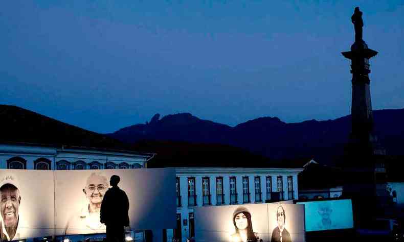 De noite, veem-se fotos iluminadas do Projeto Moradores expostas na Praa Tiradentes, em Ouro Preto