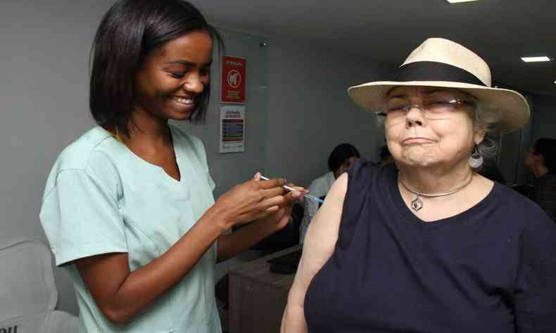 uma idosa recendo a vacina da gripe de uma enfermeira