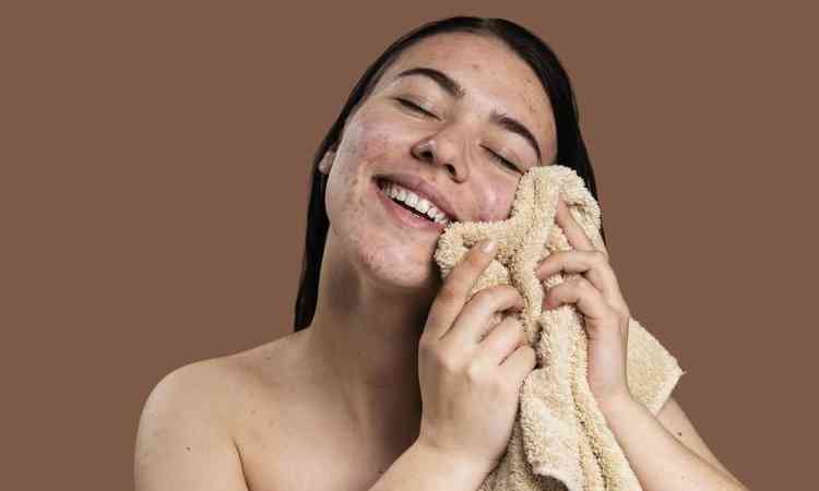 mulher sorridente secando o rosto com uma toalha