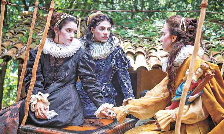 Trs atrizes com figurinos do sculo 16 conversam em cena do filme As rfs da rainha
