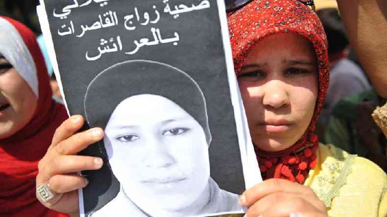 Amina Filali, na imagem em preto e branco, se matou aos 16 anos aps ser obrigada a casar com seu estuprador. Sua irm, Hamida, que segura o cartaz nesta foto, participou de protestos que levaram  mudana da lei no Marrocos(foto: Getty Images)