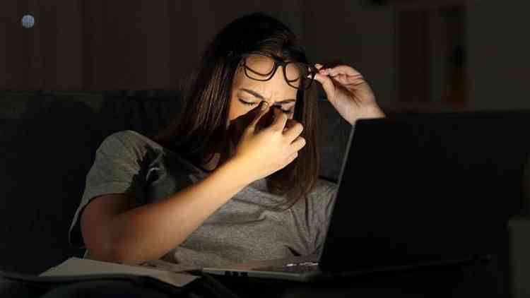 Mulher com feio preocupada em frente a laptop em ambiente escuro