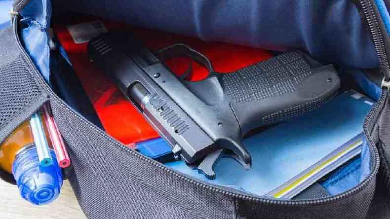 Arma guardada dentro de mochila ao lado de caderno