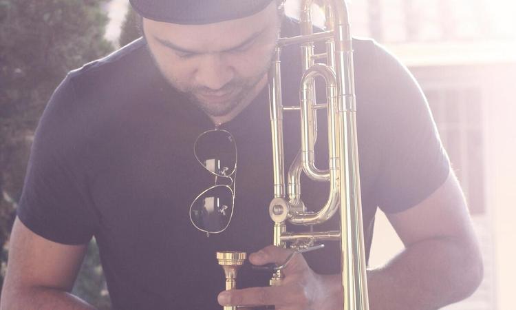 Msico Pedro Aristides olha para baixo, segurando o trombone
