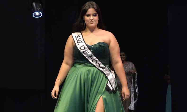 Modelo plus size Luiza Peraccini Milagre desfila, usando top preto e saia longa verde-bandeira e faixa onde se l Juiz de Fora