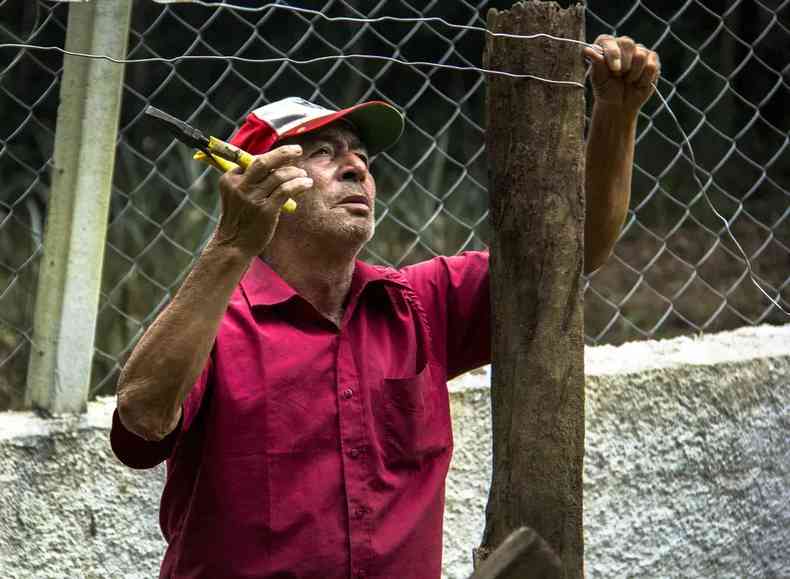 Idoso conserta cerca de propriedade