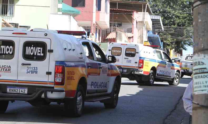 Carros da Polcia Militar, de cor branca, amarela, azul e vermelha passando em uma rua de Belo Horizonte.