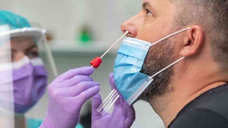Profissional da sade coloca haste flexvel no nariz de paciente para realizao do teste de covid-19