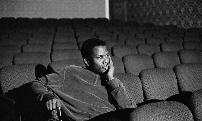 o ator Sidney Poitier numa sala de cinema, com a mo no rosto