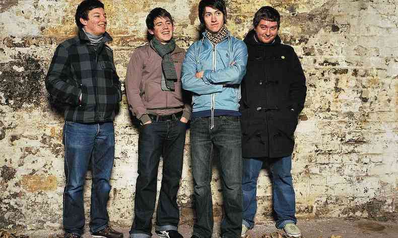 Quatro msicos da banda Arctic Monkeys, em 2006, diante muro de pedras amarelas