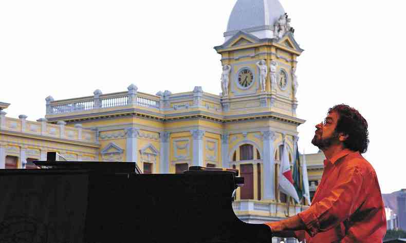 Wagner Tiso toca piano na Praa da Estao, em BH, tendo ao fundo o prdio da antiga estao ferroviria da capital mineira