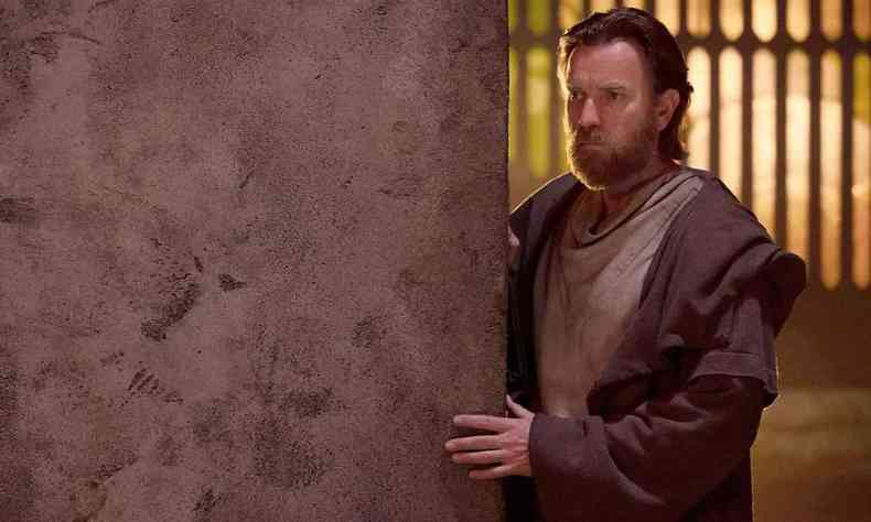 O ator Ewan McGregor observa cena encostado em uma parede 