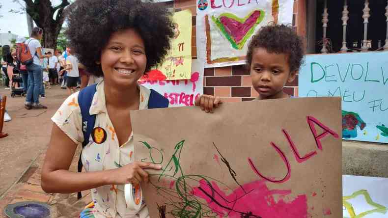 Me com filho pequeno segurando cartaz feito  prpria mo escrito Lula