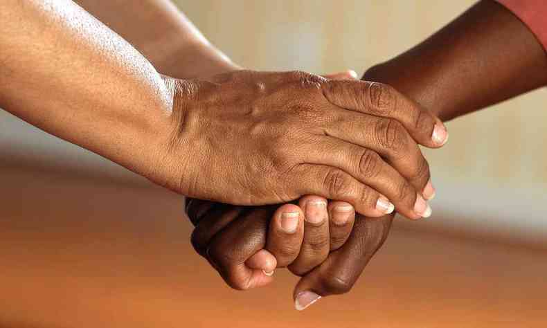 Foto em close de duas pessoas negras dando as mãos