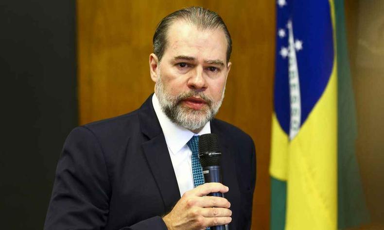 Ministro Dias Toffoli é internado com Covid-19 e não tem previsão de alta(foto: Marcelo Camargo/Agencia Brasil) Ministro Dias Toffoli de terno preto falando ao microfone com bandeira do Brasil ao fundo