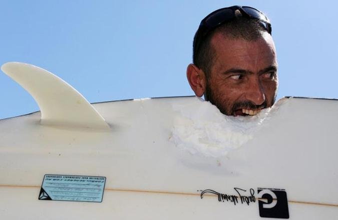 Surfista brinca com a prancha que ficou danificada depois de um ataque onde ele perdeu dois quilos de m�sculos da coxa com uma mordida de tubar�o(foto: TORSTEN BLACKWOOD / AFP)
